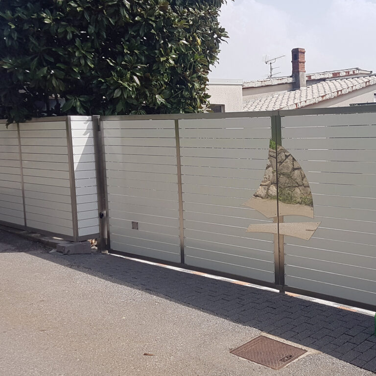 Moderna metalna vrata s horizontalnim bijelim panelima, s izrezanim dizajnom jedrilice. Ovaj elegantni ulaz prikazuje ograde od nehrđajućeg čelika i jedrilice, koje stoje pokraj stabla s popločanim pločnikom i zgradama u pozadini.